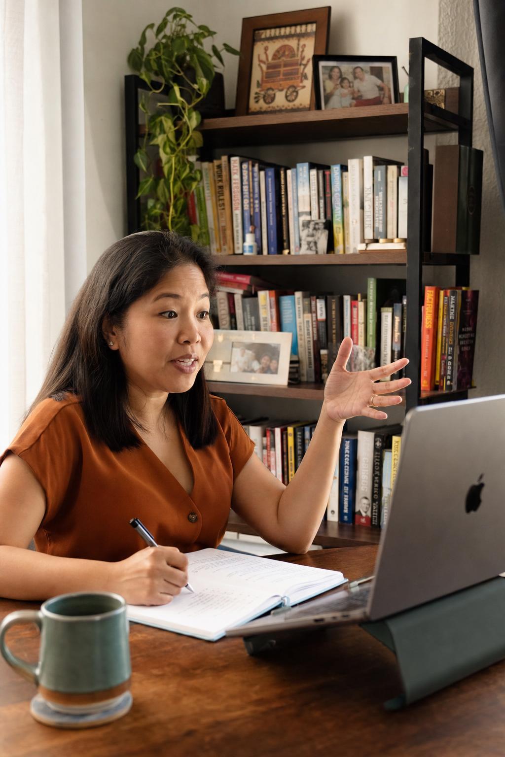A Filipino professional in her home office on a video call, gesturing while explaining something.